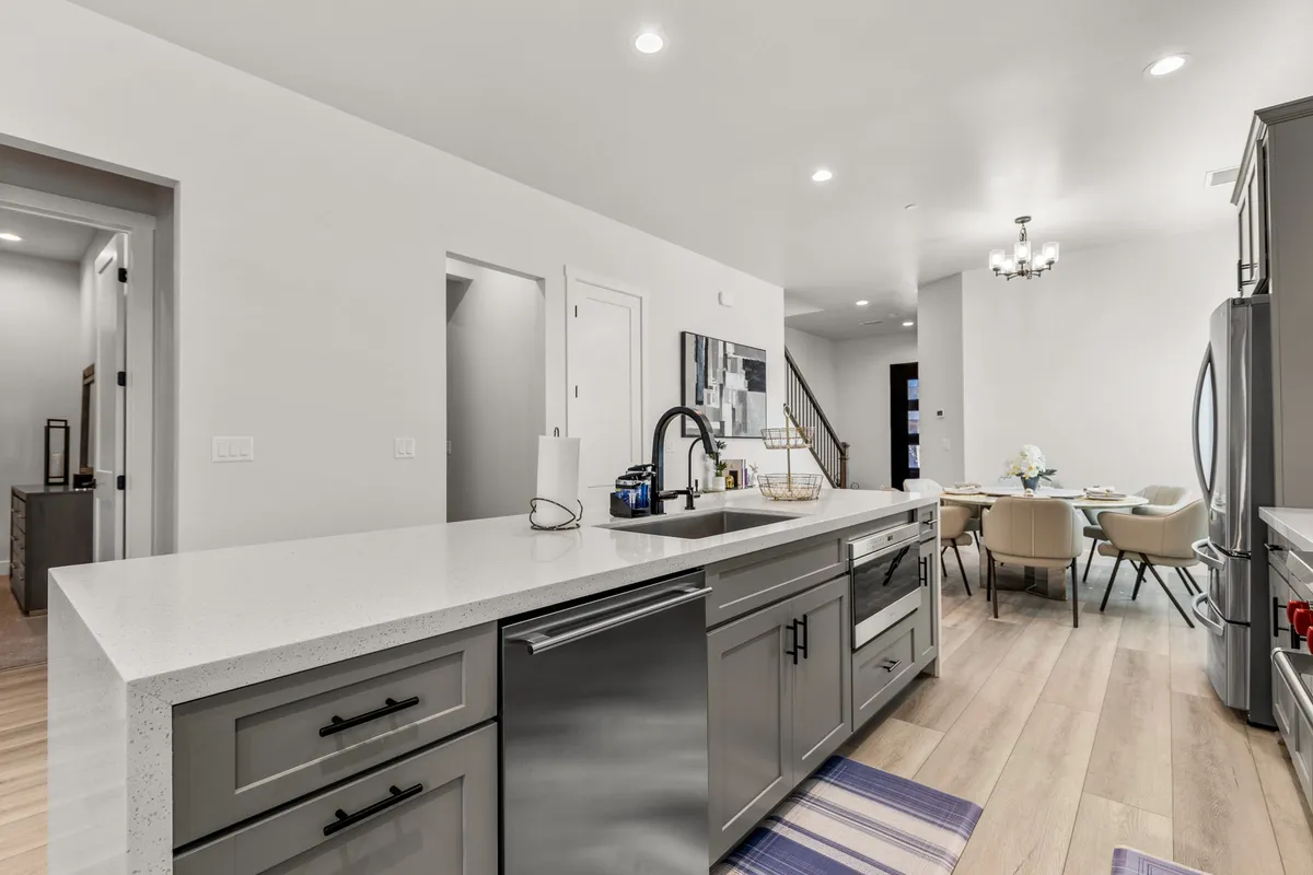 A spacious open-plan kitchen and dining area, complete with a kitchen island, stainless steel appliances, and decorative artwork. The layout encourages both cooking and connection, and the adjacent dining area is ideal for celebratory dinners or family meals.