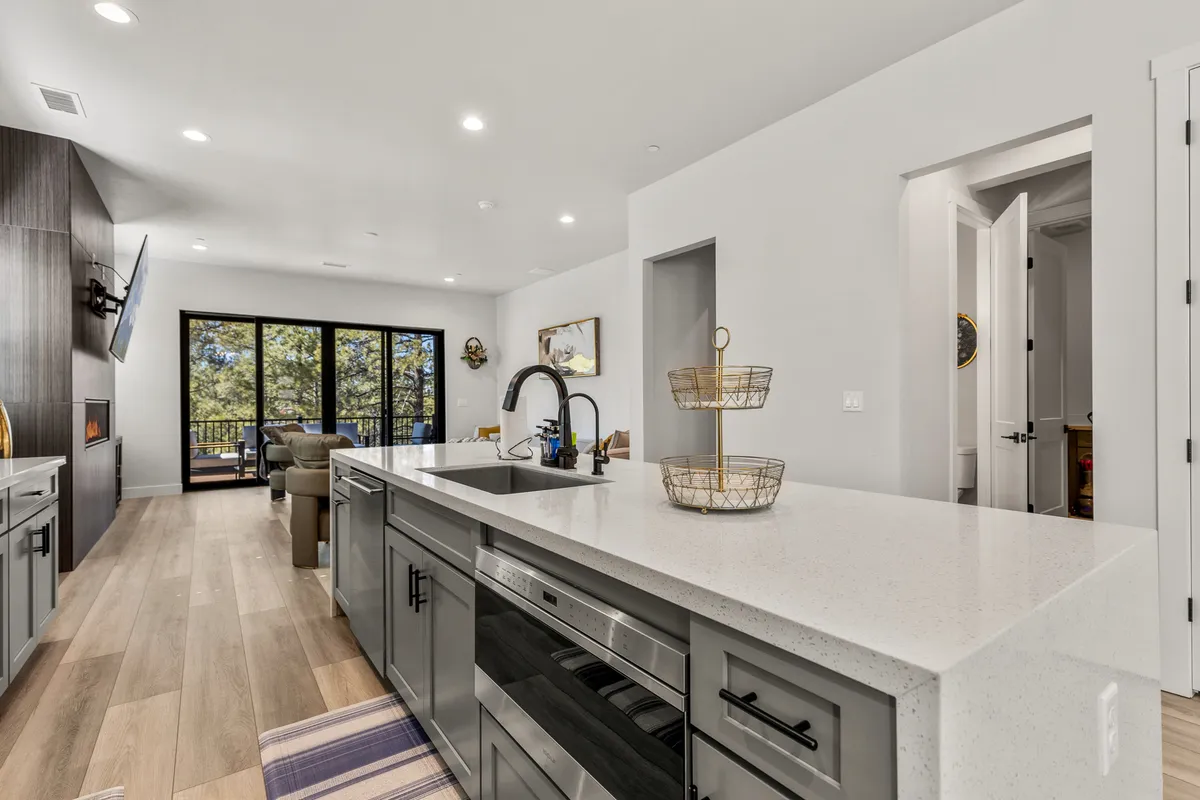A contemporary kitchen with a large island, modern stainless steel appliances, and generous counter space. Large windows allow natural light to flood the space, and a seating area is visible, suggesting a social and welcoming environment. The overall atmosphere is both stylish and functional, ideal for gathering and entertaining.