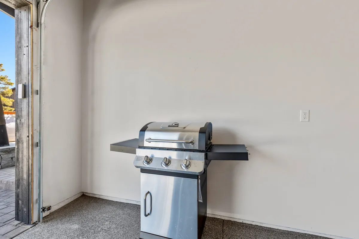 A casual setting featuring a grill just outside an open doorway, suggesting a seamless transition between indoor and outdoor entertaining spaces. The inviting atmosphere hints at shared meals and socializing after graduation ceremonies.