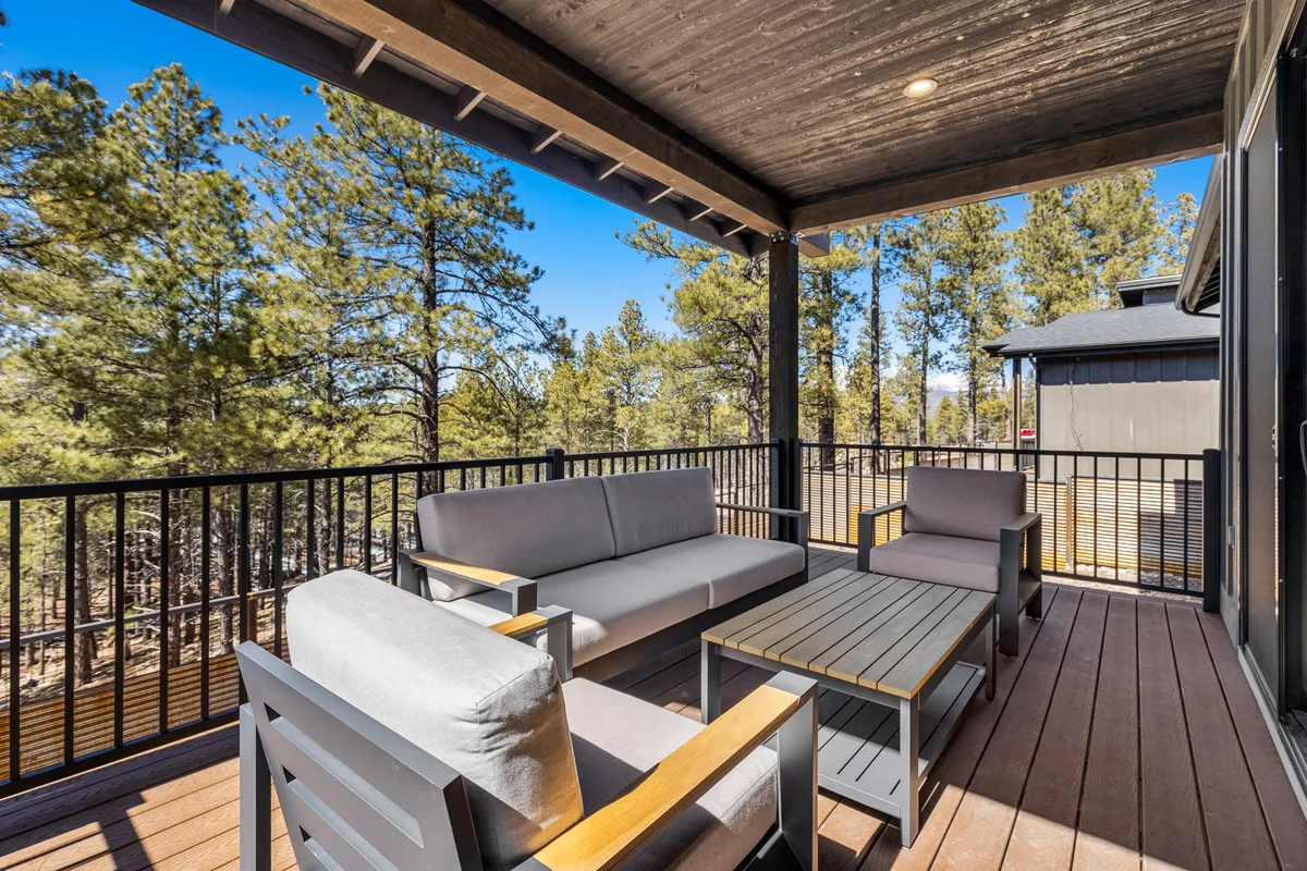 An inviting outdoor seating area nestled among surrounding trees, featuring a wooden table and comfortable chairs. The tranquil setting highlights opportunities for relaxing, sharing family meals, or gathering with friends amidst nature.