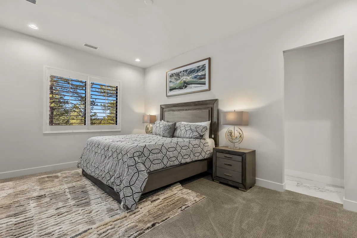 A serene bedroom featuring a well-made bed, nightstands, a window letting in soft natural light, and tasteful wall art. The space feels restful and is designed for relaxation and privacy.